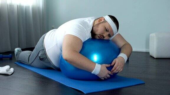 意志薄弱的胖子在健身球上放松在家锻炼休息懒惰