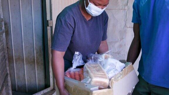 在南非一名非洲黑人男子给受新冠肺炎疫情影响严重的穷人和饥饿者送食物包裹