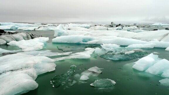 在冰岛南部海岸的Jokulsarlon泻湖上无人机在漂浮的冰山上空飞行