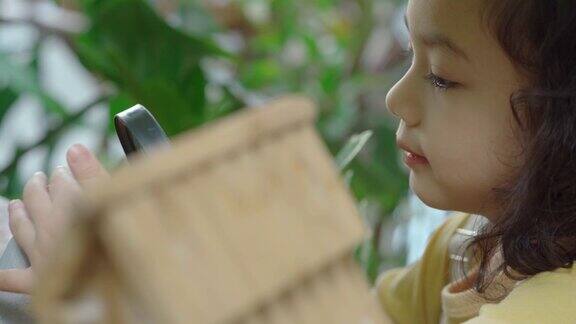 亚洲小女孩用放大镜研究生物学在家种植植物在家教育