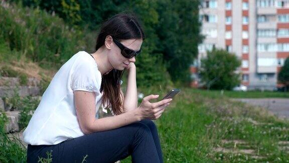 女人坐在公园里用手机发信息