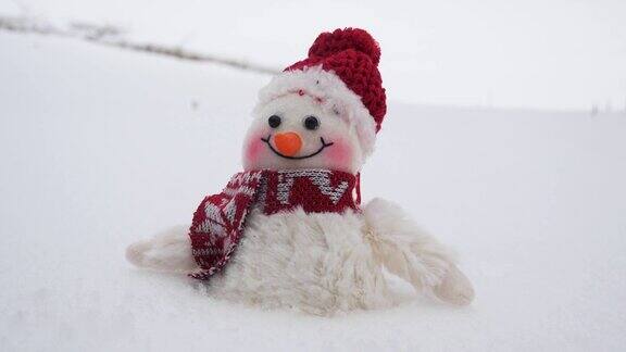 一个玩具雪人在冬天的雪堆里戴着红帽子
