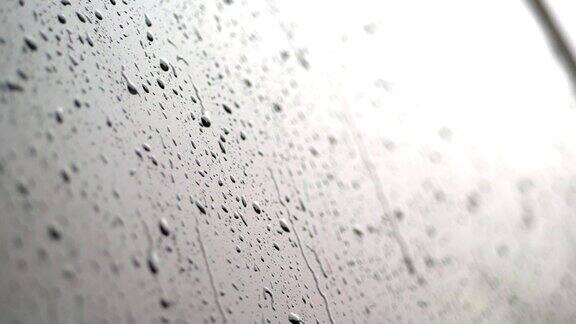 特写镜头雨点在汽车的玻璃窗上滴落下来雨下得很大下着倾盆大雨雨滴落在汽车玻璃上