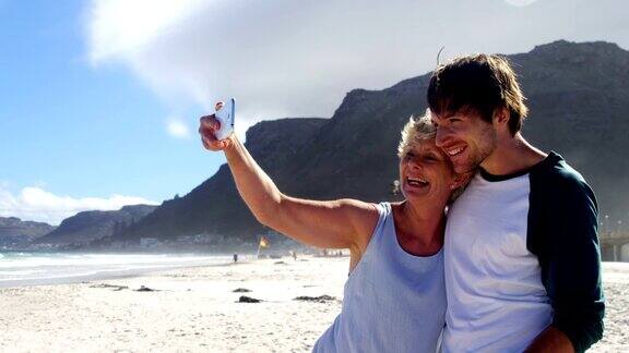 母亲和儿子在海滩上用手机自拍
