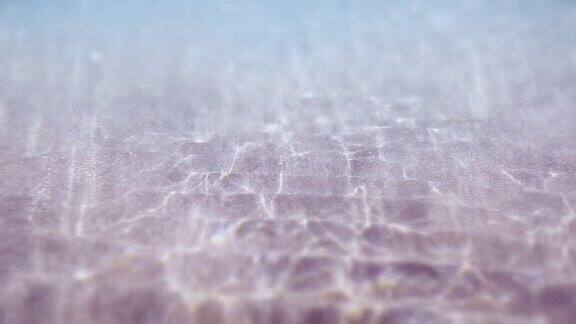 水下沙质海底水波搅动着沙子一片沙滩阳光穿过海洋抽象背景慢动作无缝循环