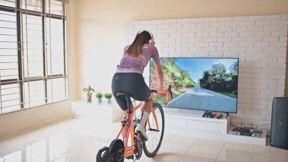 亚洲中国妇女骑自行车与固定自行车教练在家
