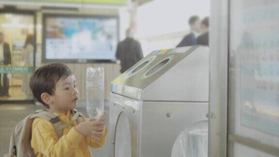 亚洲男婴将塑料瓶扔进可回收垃圾箱