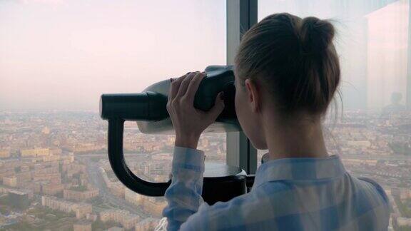 年轻女子通过观光望远镜探索壮观的城市景观