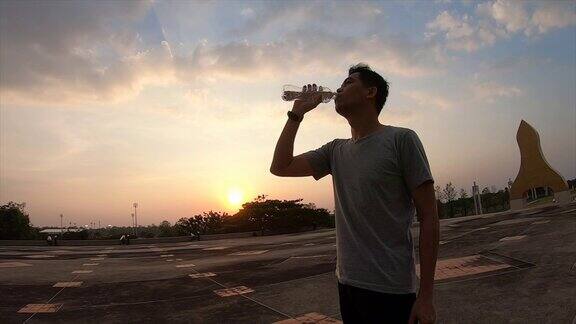 亚洲健身男子跑步者饮用瓶装水在户外跑步慢跑
