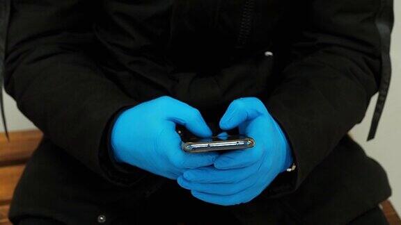 COVID-19冠状病毒一个戴着手套的男人在用手机