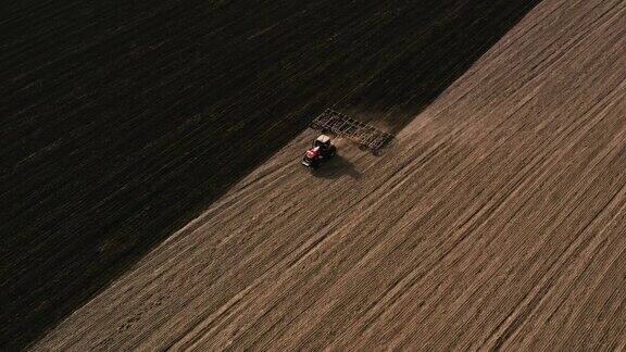 农民开拖拉机和播种机在田野上播种