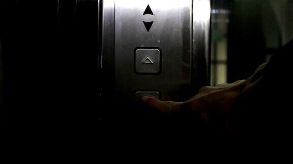 一个年轻女孩的手按下了电梯召唤按钮