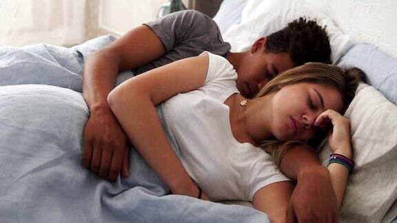 多种族夫妇躺在床上拥抱着对方睡觉的特写年轻的家庭概念