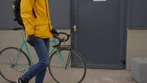 一个无法辨认的白人男子穿着黄色夹克上下班时推着自行车