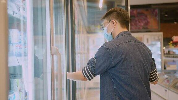 亚洲男性在超市或商店购买食品杂货时戴着防冠状病毒的医用口罩健康、安全和大流行在隔离期间购物