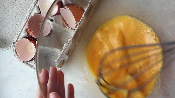 妇女用打蛋器打鸡蛋准备自制煎蛋卷特写慢动作烹饪