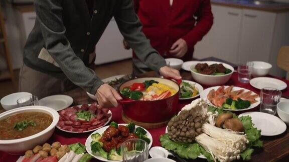 亚洲媳妇和大妈在家里准备年夜饭的时候在桌子上端上一锅热汤寓意“福”的柜体文字