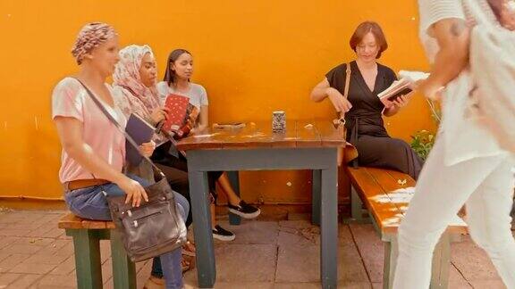 一群年轻女子坐在咖啡馆的长凳上