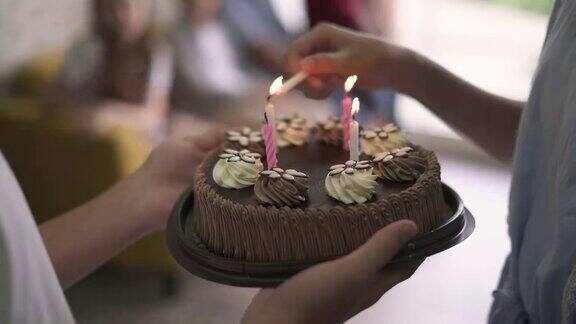 女孩的手点燃生日蛋糕上的蜡烛