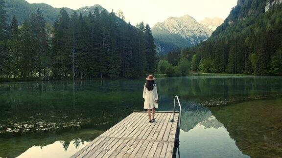 慢镜头:年轻女子沿着湖上的木码头走着