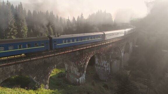 一列火车在清晨穿过一座美丽的石桥的航拍照片