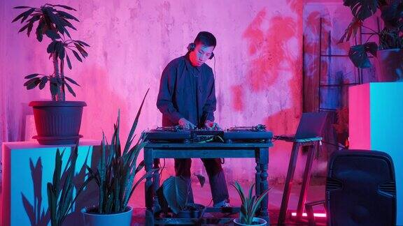 AsianAppearance的现代DJ在霓虹灯下演奏音乐