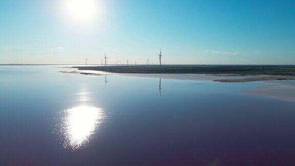 无人机飞过湖岸背景是风力发电场