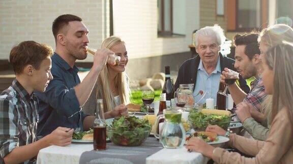 一群混合种族的人有乐趣交流和吃在户外家庭晚餐
