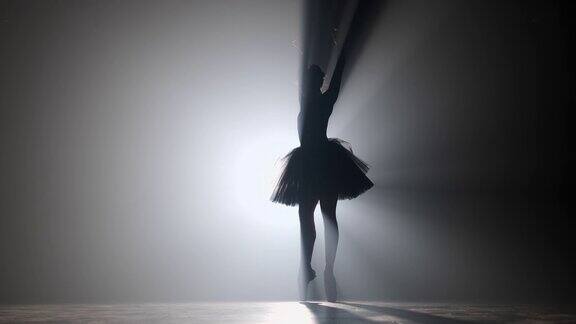 芭蕾舞演员穿着黑色礼服在聚光灯下跳芭蕾舞