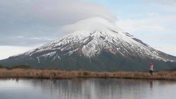 游客漫步在新西兰北岛的塔拉纳基火山与山和登山者在湖中的倒影在一起新西兰被