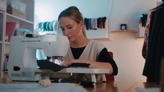 年轻的女裁缝在她的工作室用缝纫机缝纫