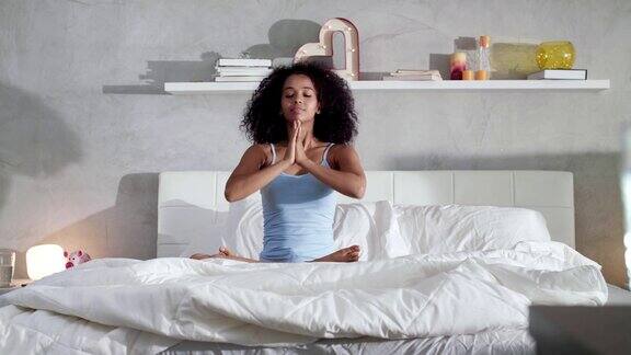 年轻的非洲裔美国妇女在床上做瑜伽