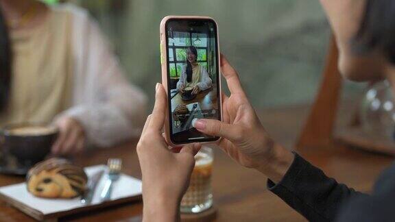 一群亚洲女性朋友在咖啡店见面一起用智能手机自拍
