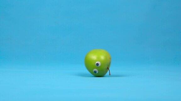 绿苹果眼睛慢慢转动蓝色背景上的苹果卷缓慢的运动