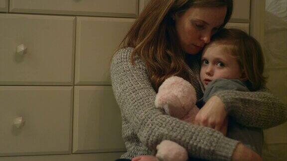 伤心害怕的小女孩抱着她妈妈的毛绒玩具在她的房间里