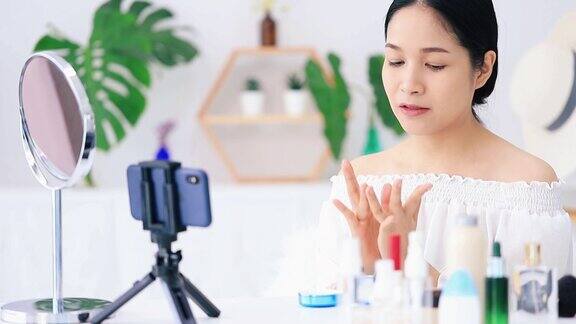 美丽的亚洲女人博客展示如何化妆和使用化妆品在智能手机前录制视频直播在家商业在线影响者对社交媒体
