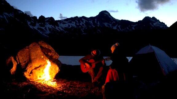 黄昏时分一对旅行者在篝火旁