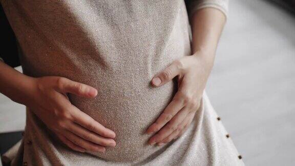 孕妇在她的肚子上做了一个心形的手势