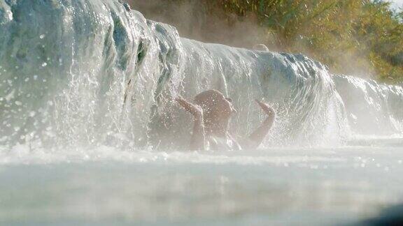 女人享受热水瀑布在温泉里