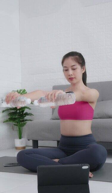 一个20-30岁的亚裔女性穿着运动酒吧的肖像利用家里的器材来锻炼身体靠近客厅的沙发