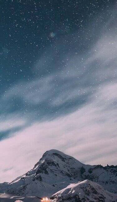 时间流逝的近距离观看惊人的明亮的山顶覆盖的雪冬季自然景观Hyperlapse垂直镜头视频从晚上到晚上的过渡大胆的蓝色背景天空