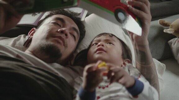 亚洲父亲和孩子在睡觉前看书