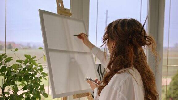 SLOMO一位年轻的女画家一边用手机画基本形状