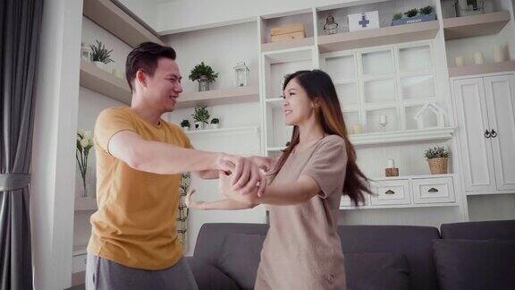 年轻的亚洲幸福夫妇在客厅跳舞夫妇放松和花时间在一起在家里