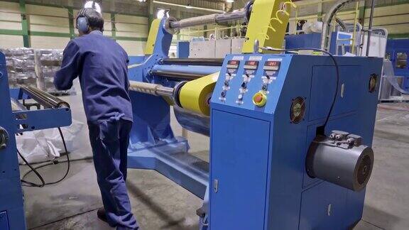 在层压板塑料制造回收生产线上更换层压板辊的西班牙男性工人