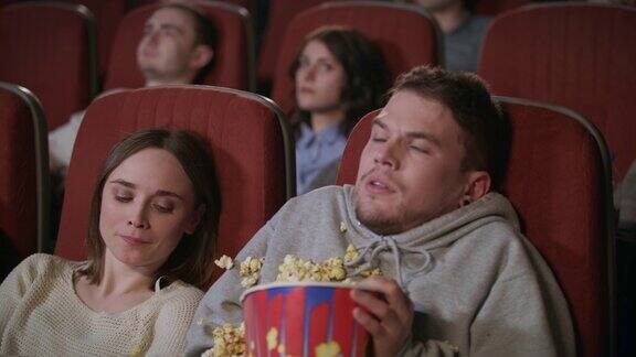 一对年轻夫妇在电影院看恐怖电影人撒爆米花