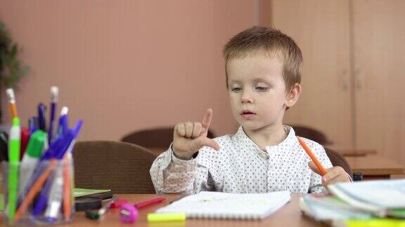 一个英俊的三岁男孩坐在课桌前思考着答案