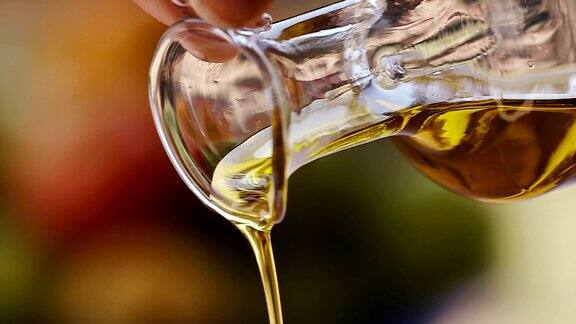 慢镜头特级初榨橄榄油被倒出一个透明的玻璃瓶