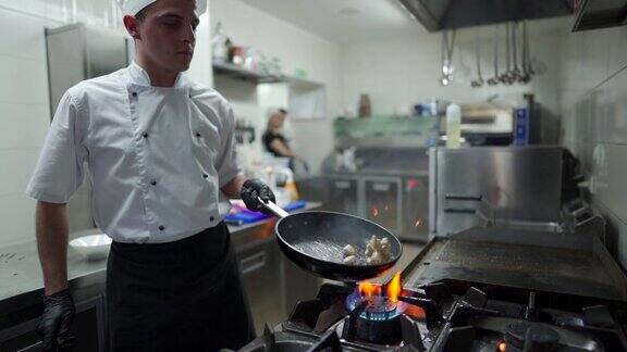 厨师在商业厨房的煎锅里搅拌碎鸡胸肉