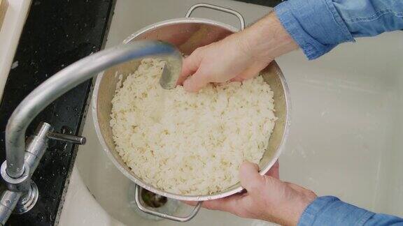 男人在水槽的滤锅里洗白米的特写